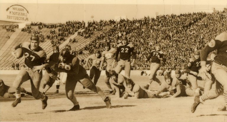 1939 Lubbock State Champion Football Team ball carrier rushing past a tackler before a packed stadium, in a sepia game photo