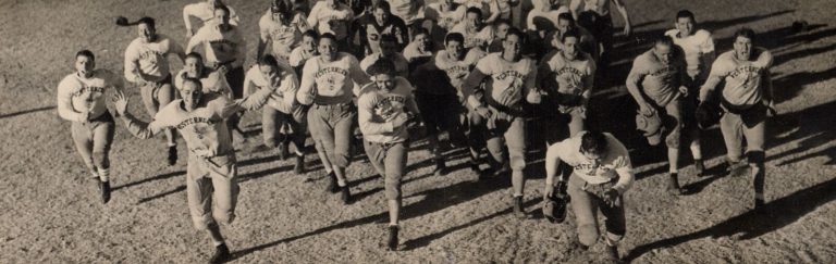 1939 Lubbock State Champion Football Team players in Westerners shirts running toward the camera across the field