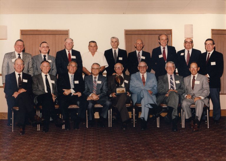 1939 Lubbock State Champion Football Team reunion group posed in two rows with a football trophy