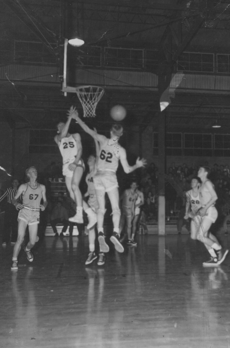 1951 Lubbock State Championship Basketball Team players leaping for a rebound near the basket in a crowded gym