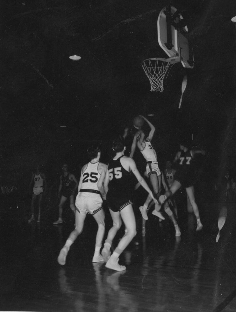 1951 Lubbock State Championship Basketball Team player rising to shoot near the basket in a dimly lit gym