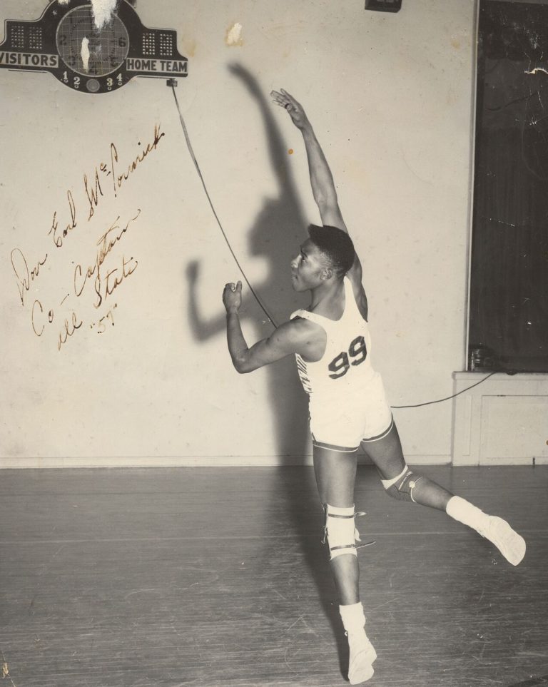 Player in a number 99 jersey reaching up in a gym, signed Don Earl McCormick; 1957 Dunbar State Championship Basketball Team