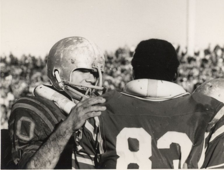 1968 Estacado Matadors Football closeup of a muddy helmeted player with a hand on the shoulder of number 83