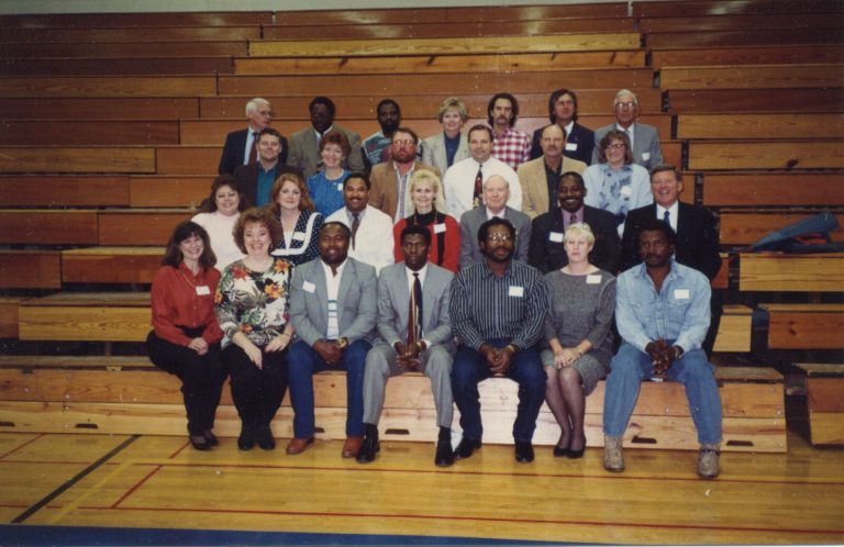 1968 Estacado Matadors Football reunion group with name tags posed on gym bleachers, 1992