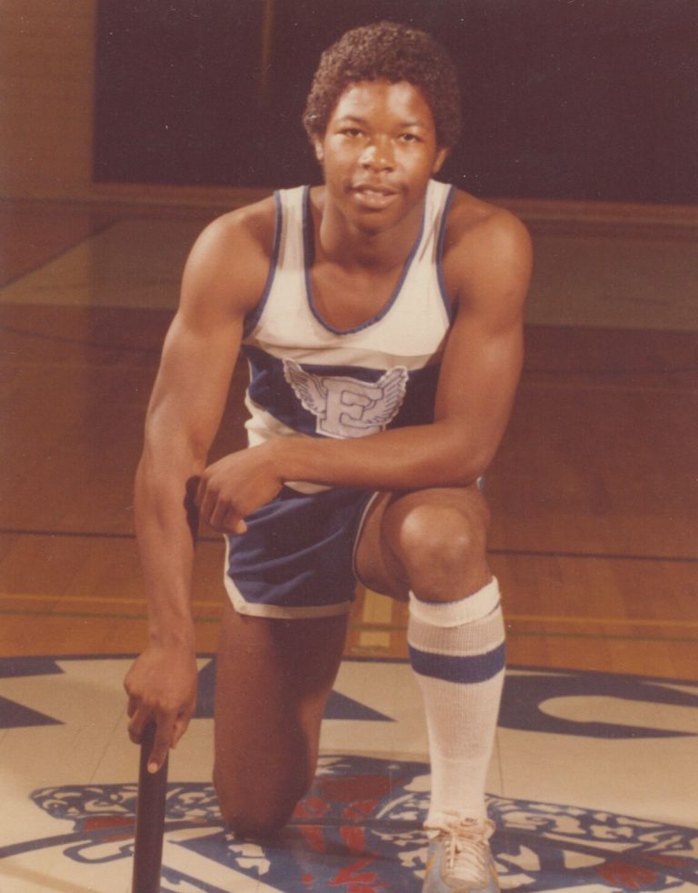 1983 Estacado High School Boys Track and Field State Champions athlete kneeling with a baton in a winged E uniform