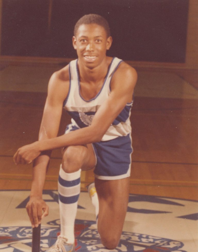 1983 Estacado High School Boys Track and Field State Champions smiling athlete kneeling with a baton in a winged E uniform
