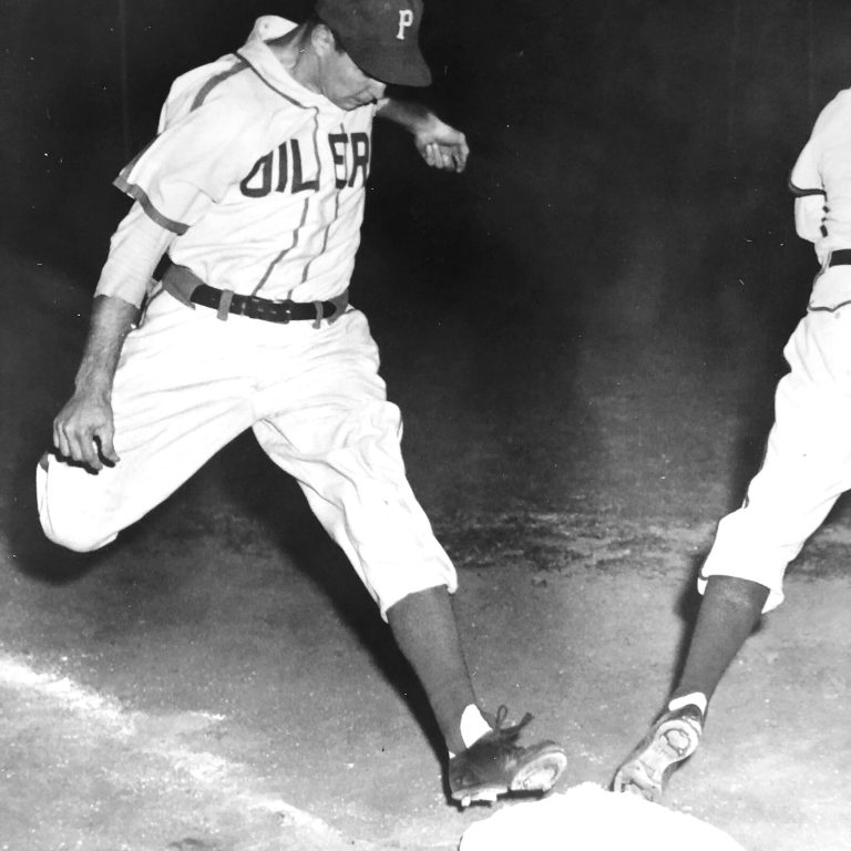 Bobby Brown in an Oilers baseball uniform stepping on a base, black and white