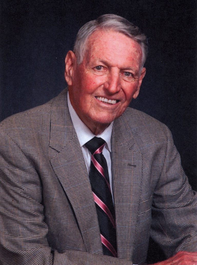 Bobby Moegle smiling in a tweed sport coat and striped tie in a formal portrait