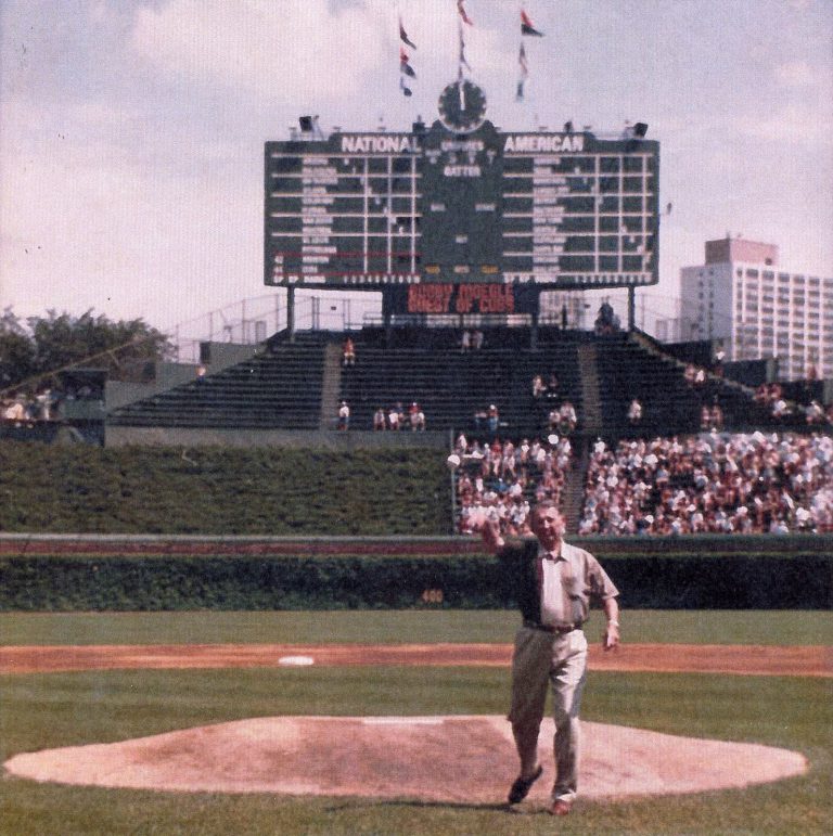 Bobby Moegle throwing a ceremonial first pitch at Wrigley Field under a Guest of Cubs message board