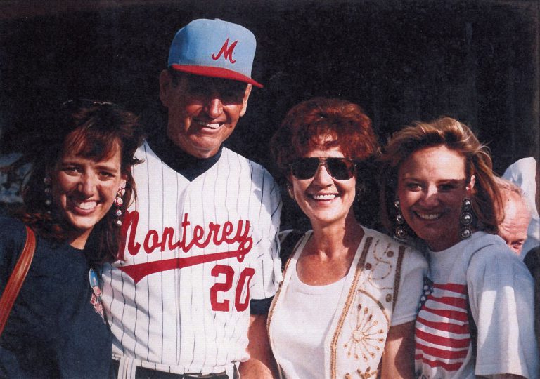 Bobby Moegle in a Monterey No. 20 pinstripe jersey posing with three smiling women