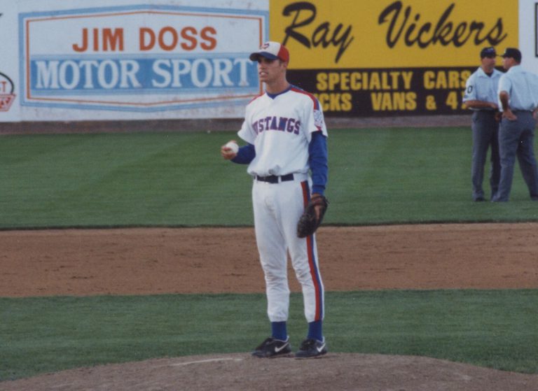 Brad Ralston on the pitcher's mound in a Mustangs uniform, holding the ball