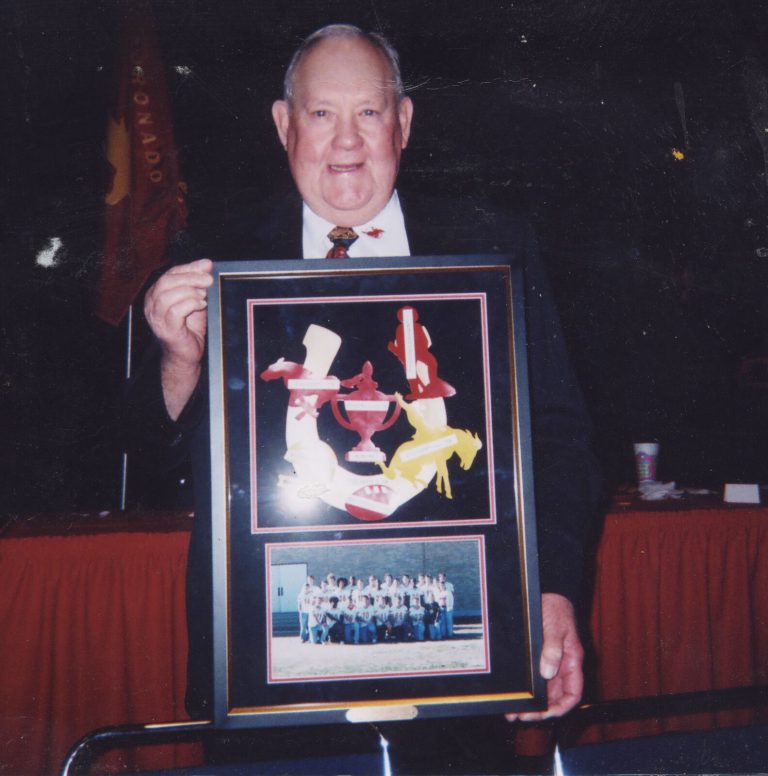 Cal Lowry holding a framed plaque with a team photo