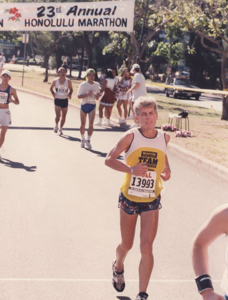Runner in a yellow team singlet under the 23rd Annual Honolulu Marathon banner, from the Caylene Caddell collection