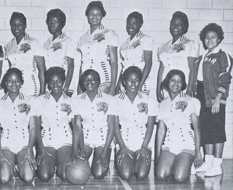 Celestine H. Kyle's Dunbar girls basketball team in white uniforms with panther logos, posed in two rows in a gym