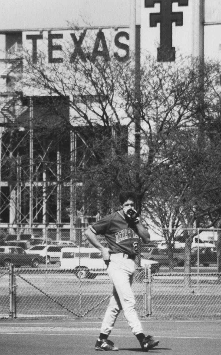Clint Bryant in a Texas Tech jersey with a glove raised to the face, a TEXAS stadium sign behind, in a black-and-white photo