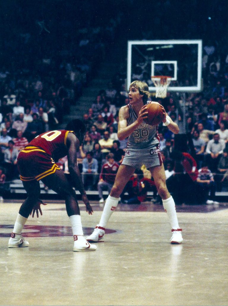 Craig Ehlo, No. 30 in a gray Washington State uniform, holding the ball against a crouching defender