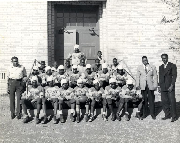 Football team in leather helmets seated on school steps with three men standing at the sides, Damon Hill, Sr. collection