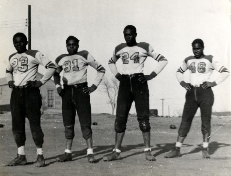 Four football players in vintage uniforms standing with hands on hips, from the Damon Hill, Sr. collection
