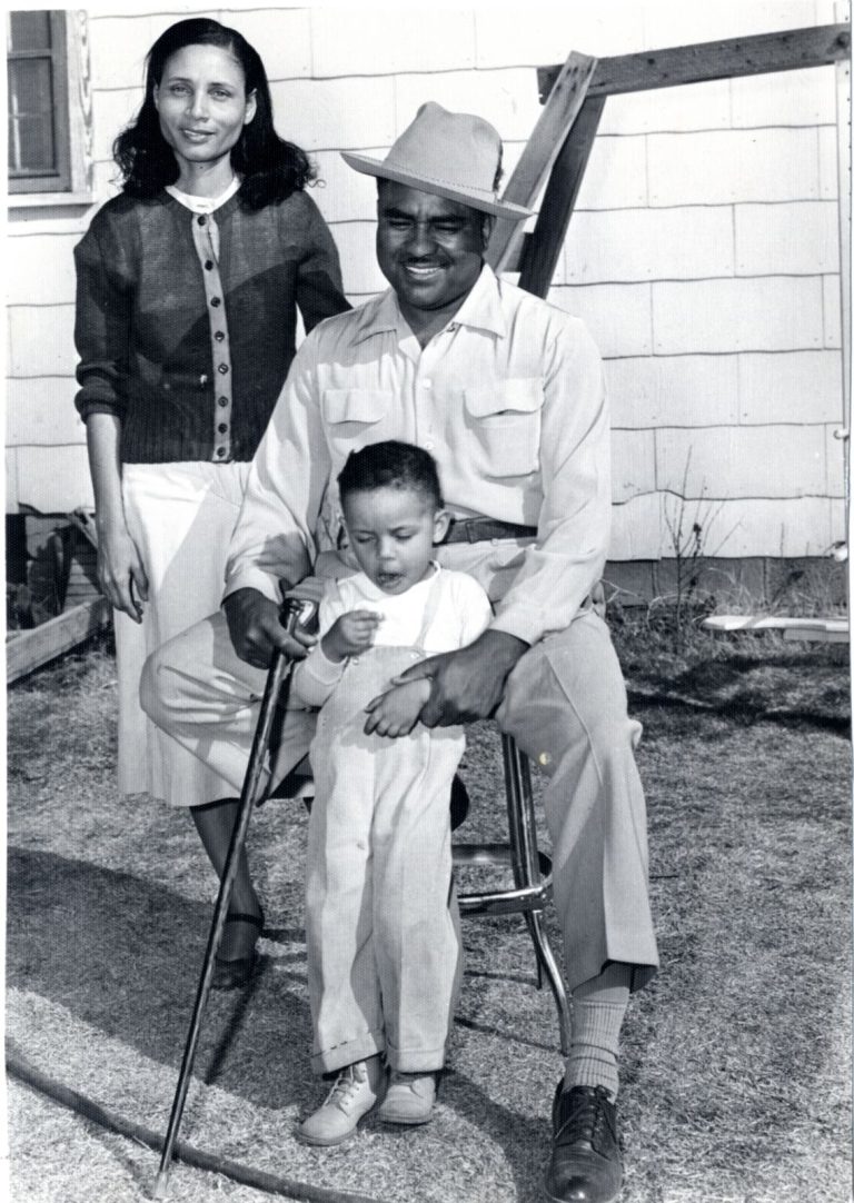 Family portrait of a man in a hat holding a small child, with a woman standing beside, Damon Hill, Sr. collection