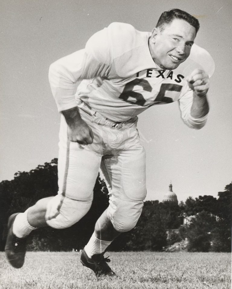 Dick Lowrey in a Texas No. 65 jersey, smiling while lunging forward in a black-and-white action pose