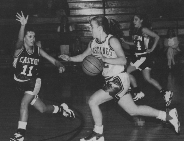 Erika Valek in a Mustangs jersey dribbling past a Canyon defender