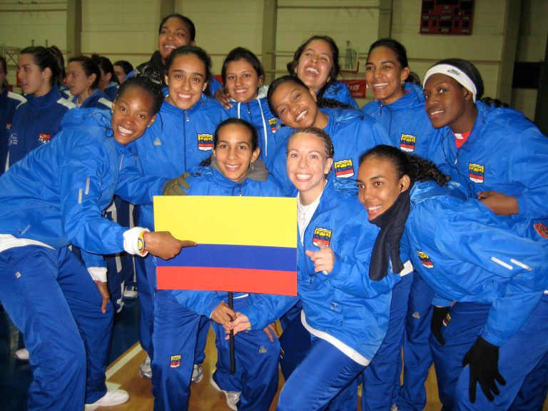 Erika Valek and Colombian teammates in blue warm-ups with a Colombian flag