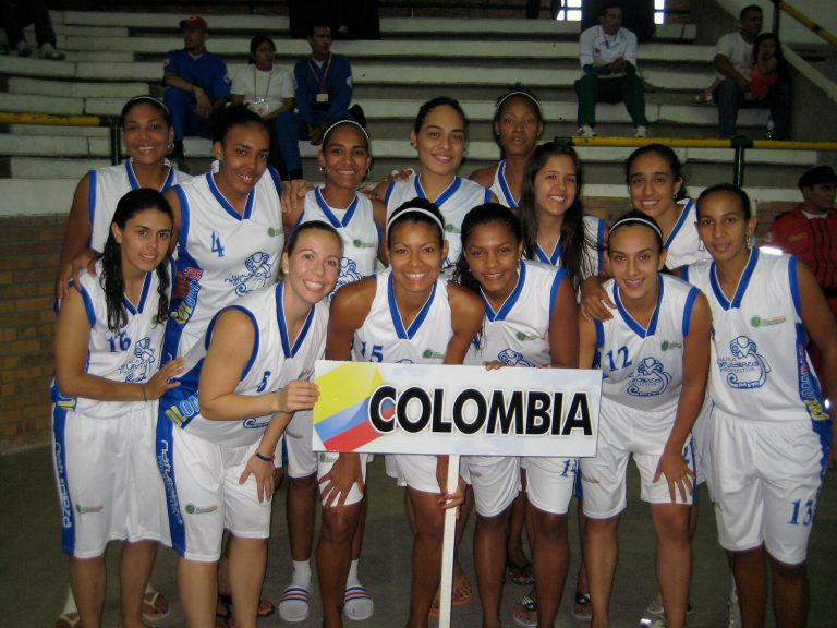 Erika Valek and the Colombian team in white and blue uniforms behind a COLOMBIA sign