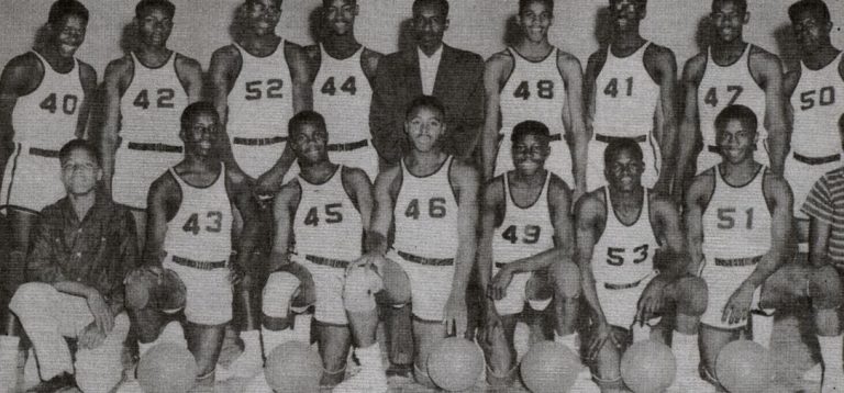 Dunbar basketball team posed in two rows with basketballs and a man in a dark jacket, from Ernest Mallory's scrapbook