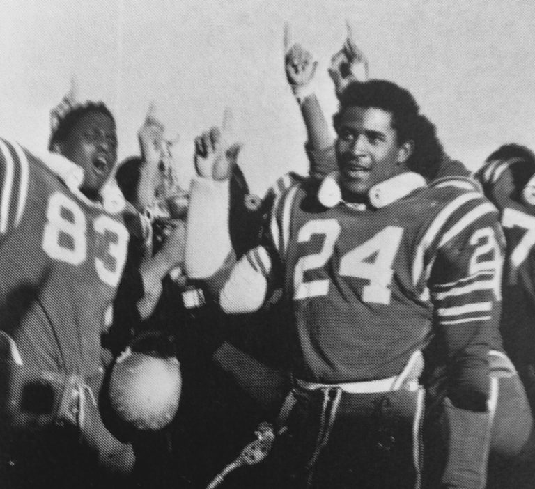 Fred White (83) and teammate number 24 celebrating with players raising index fingers