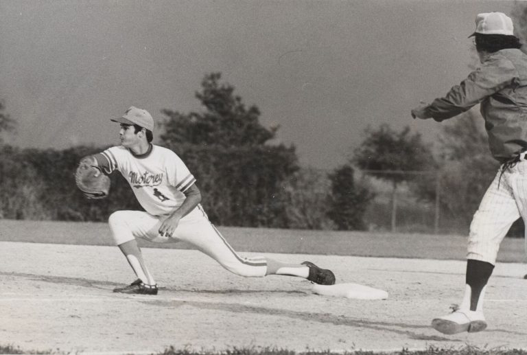 Gary Ashby stretching to catch a throw at first base in a Monterey uniform, black-and-white action shot