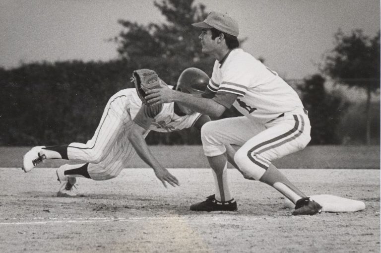 Gary Ashby at first base as a runner dives back headfirst on a pickoff play, black-and-white action shot