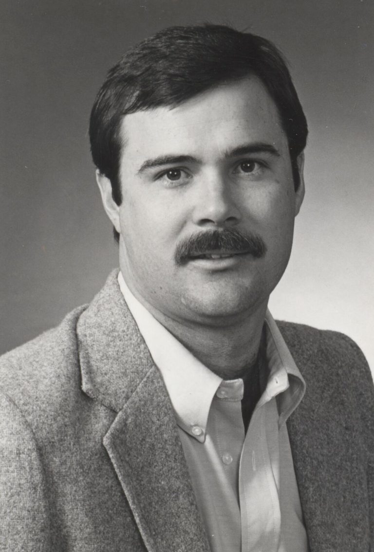 Gary Ashby in a tweed sport coat and open-collar shirt, black-and-white portrait