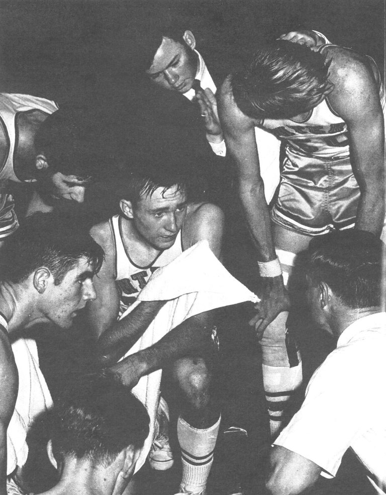 Gerald Myers' Monterey players and a coach in a tight huddle by the bench, black-and-white program photo