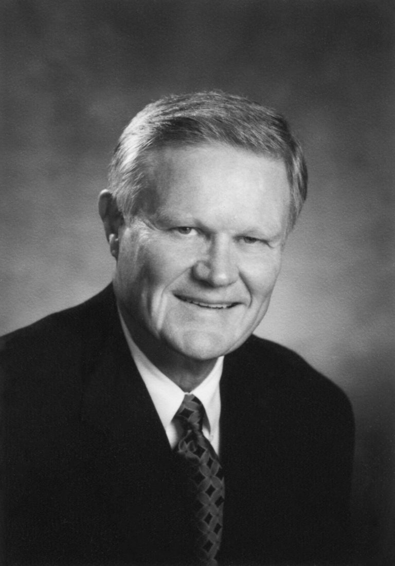 Gerald Myers smiling in a dark suit and patterned tie, black-and-white studio portrait