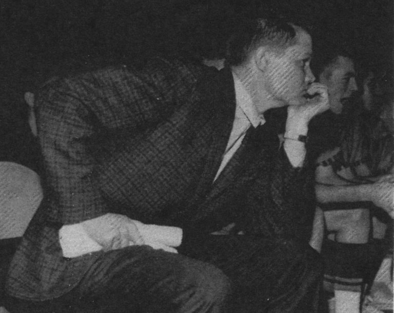 Gerald Myers leaning forward with chin on fist while watching from the bench, black-and-white yearbook photo