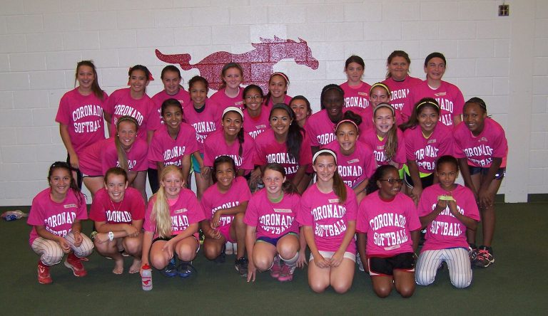 J. J. Johnson's Coronado softball players in matching pink shirts posing in front of a Mustang logo