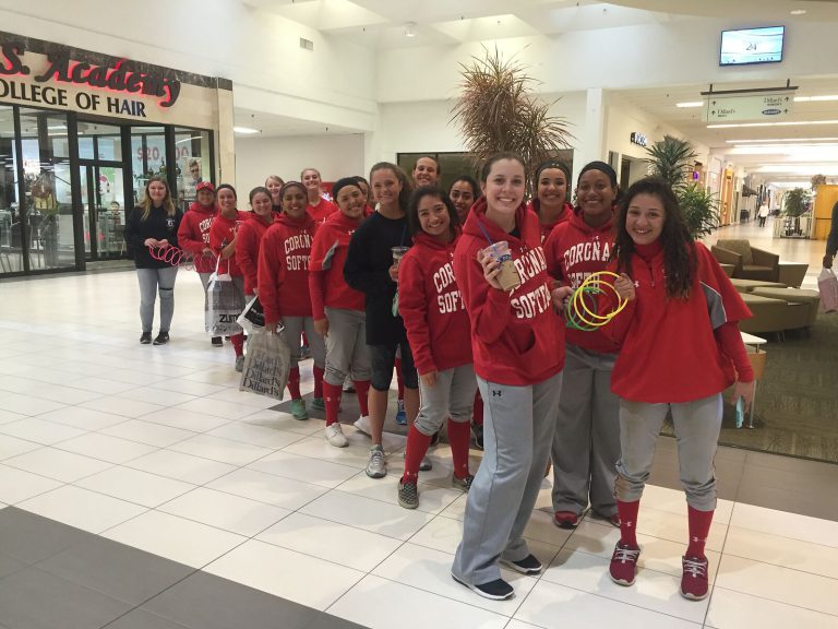J. J. Johnson's Coronado softball players in red hoodies lined up and smiling in a shopping mall