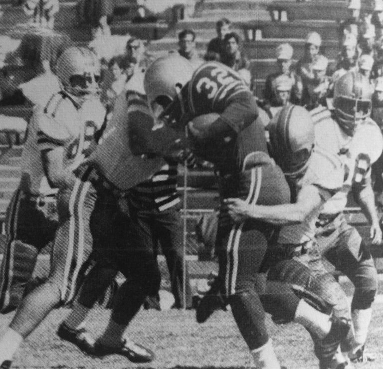 James Mosley, number 32, carrying the football through a crowd of players in a 1968 game, black-and-white photo