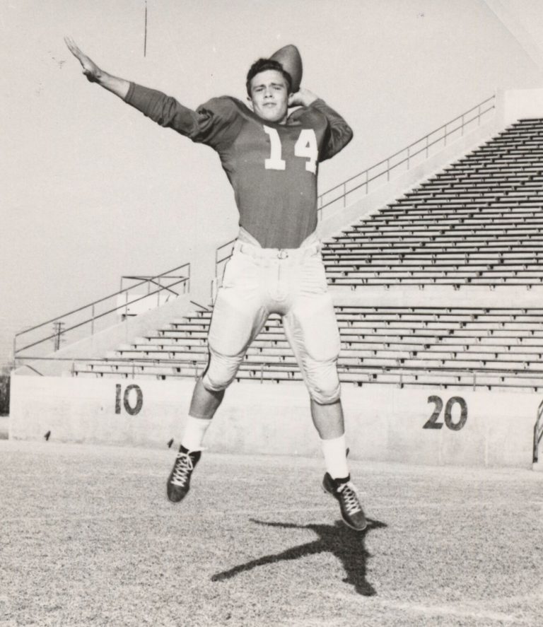 Young football player, number 14, leaping to throw in a posed stadium photo from the James Odom collection