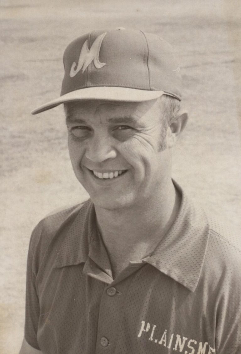 James Odom smiling in a baseball cap with an M logo and a Plainsmen shirt