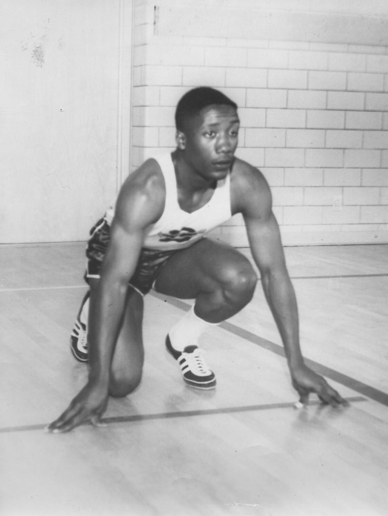 James Ray Jackson in a sprinter's starting crouch on a gym floor