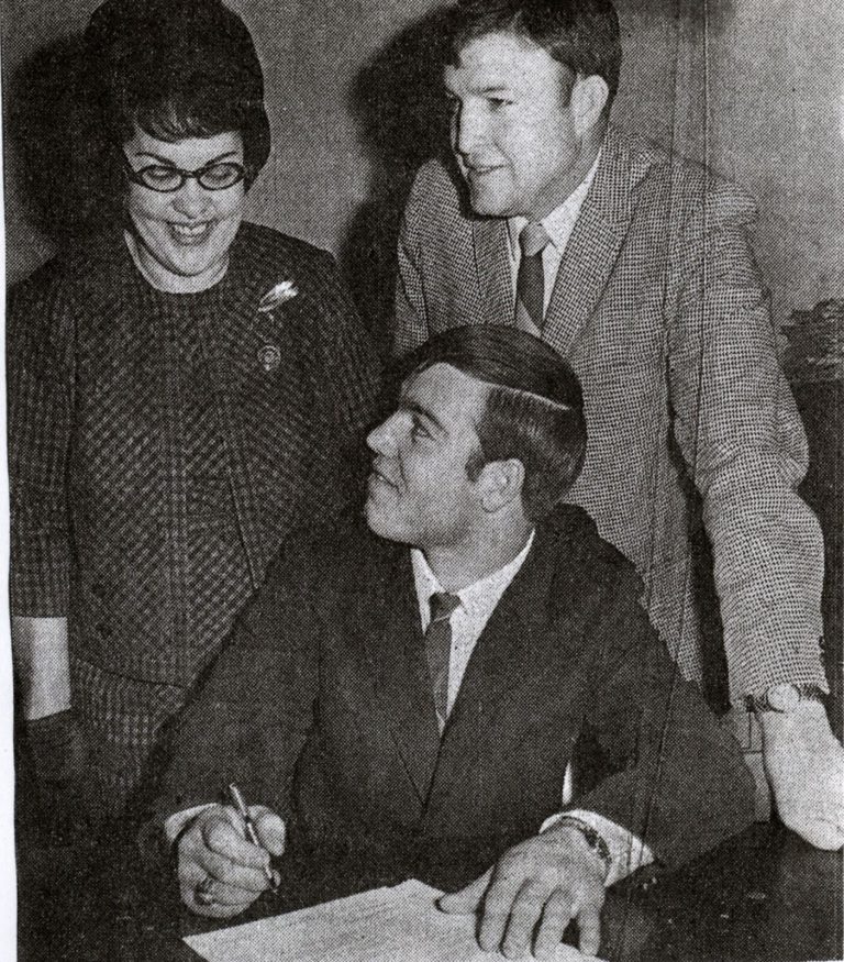 Jerry Austin signing with Angelo State as Mrs. Stogie Austin and a coach look on, from a 1969 newspaper