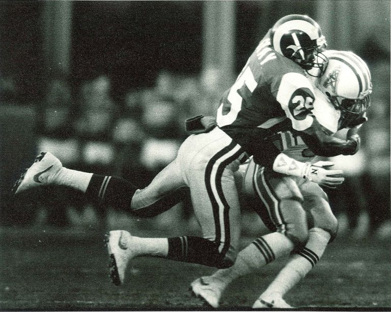 Jerry Gray, No. 25 for the Rams, tackling a ball carrier in a white helmet in a black-and-white game photo