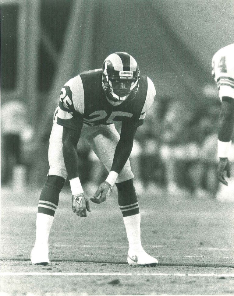 Jerry Gray, No. 25 for the Rams, bending in a ready stance on the field in a black-and-white game photo