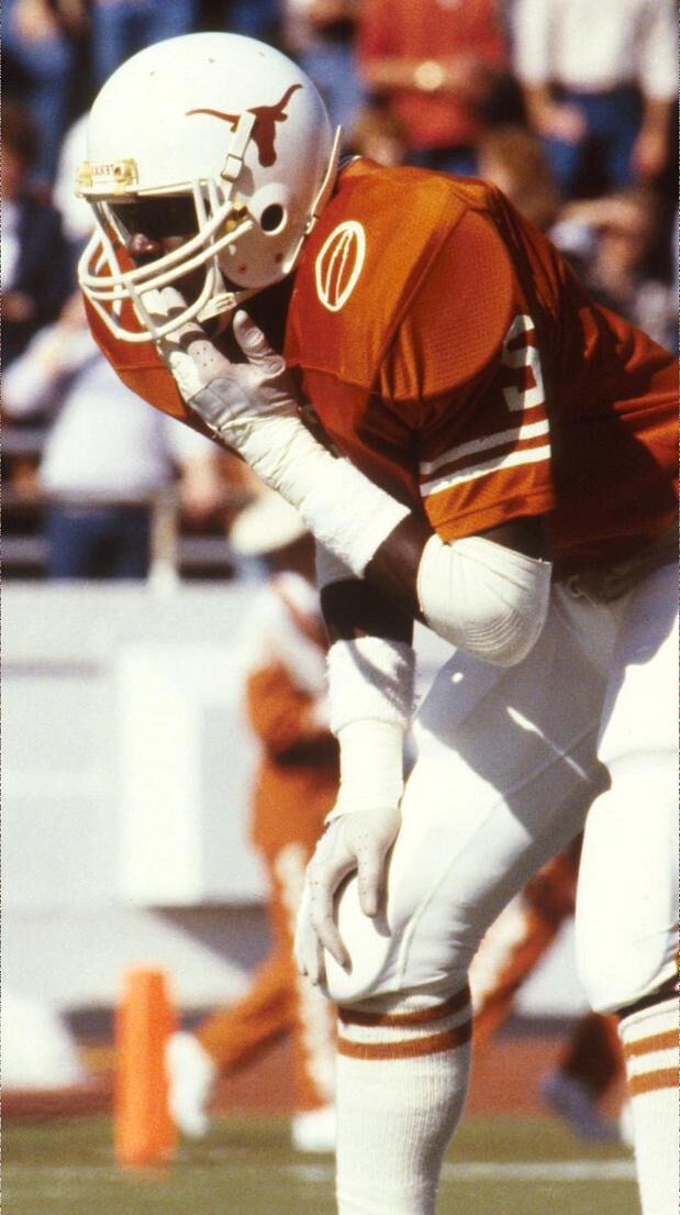 Jerry Gray in a white longhorn-logo helmet and orange jersey bending forward with a hand on a knee during a game