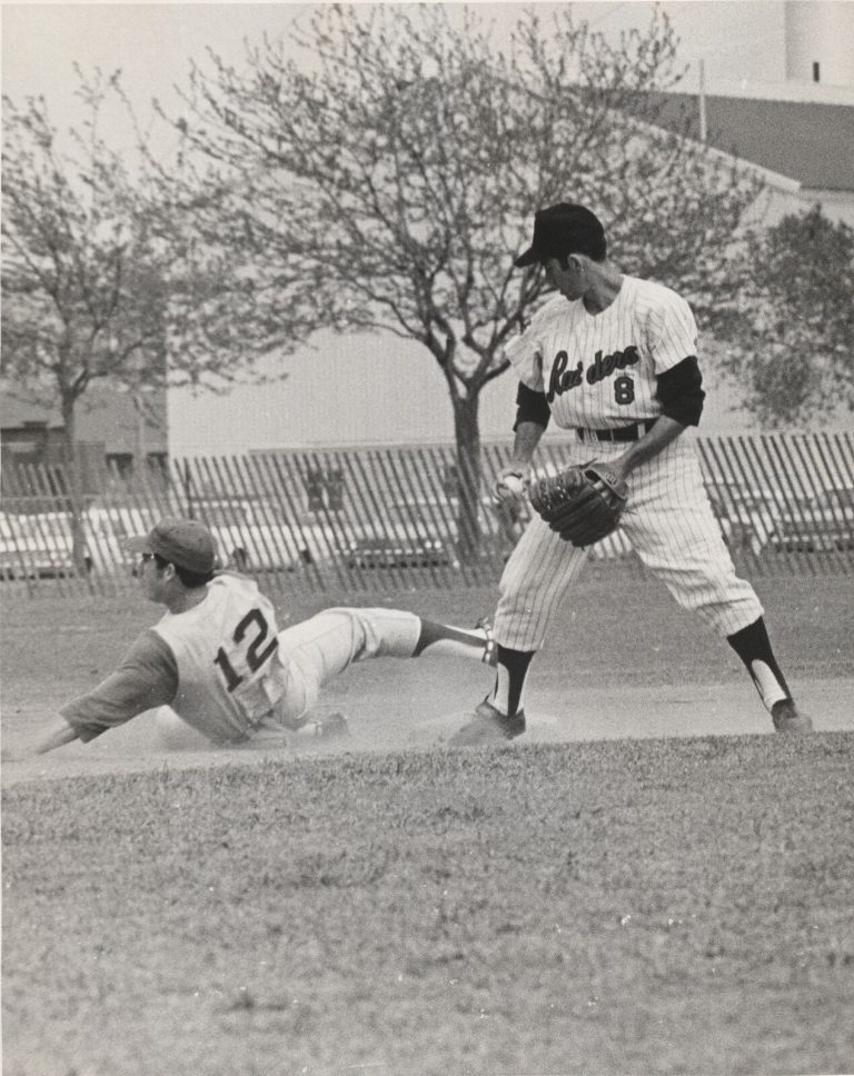 Jerry Haggard, number 8 in Raiders pinstripes, with a runner sliding in at the base, black and white
