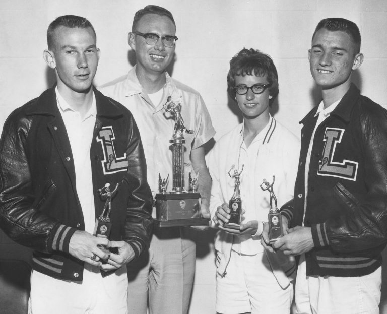 Four people holding tennis trophies, two in L letter jackets, from the Jill Philbrick Gentry collection