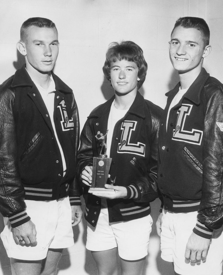 Three people in L letter jackets, one holding a small trophy, from the Jill Philbrick Gentry collection