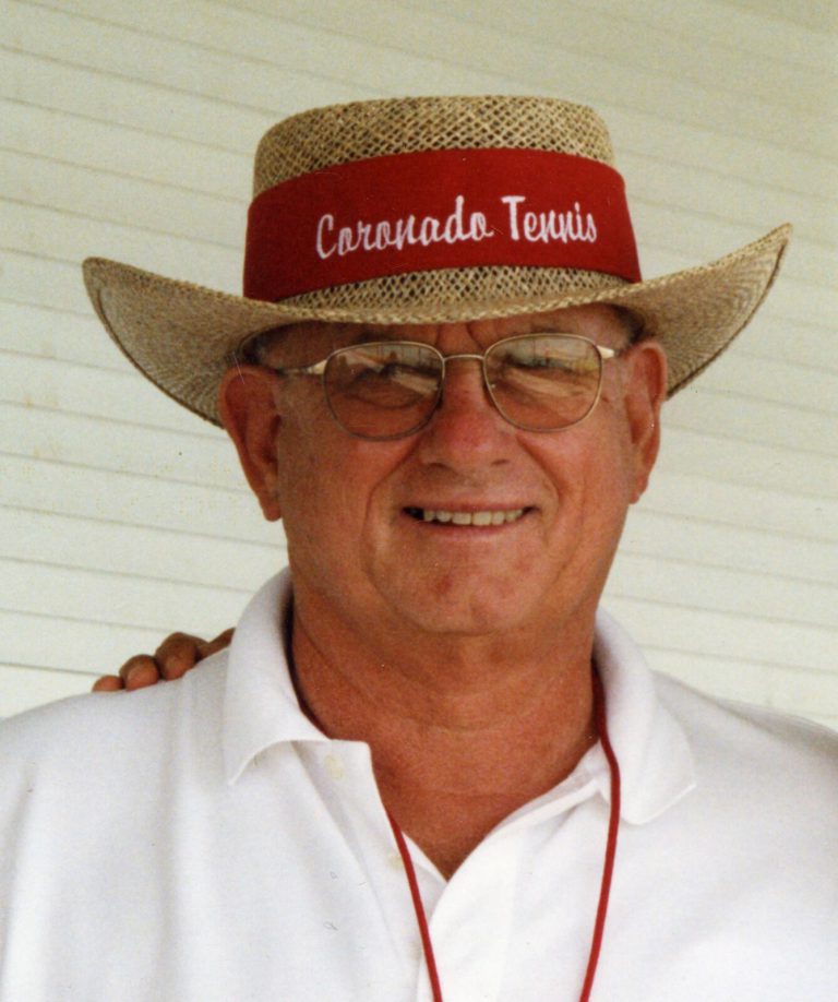 Jim Carter smiling in a straw hat with a red Coronado Tennis band and a white polo