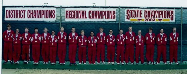 Jim Carter's tennis team in red warm-ups and medals below District, Regional and 2003 State Champions banners